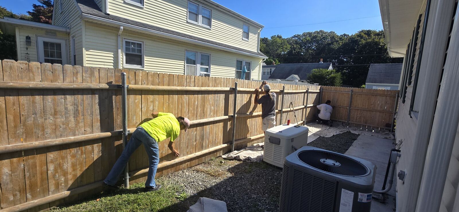 Two painters on ladders working on second story dormer of a shingle style home