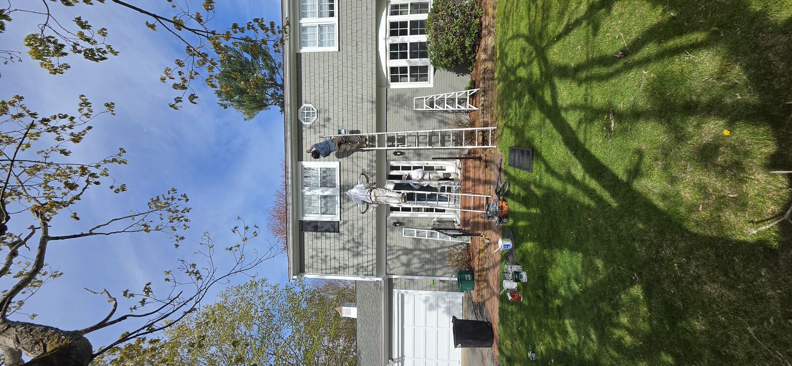 Adams Painting crew member in branded hoodie painting a home exterior